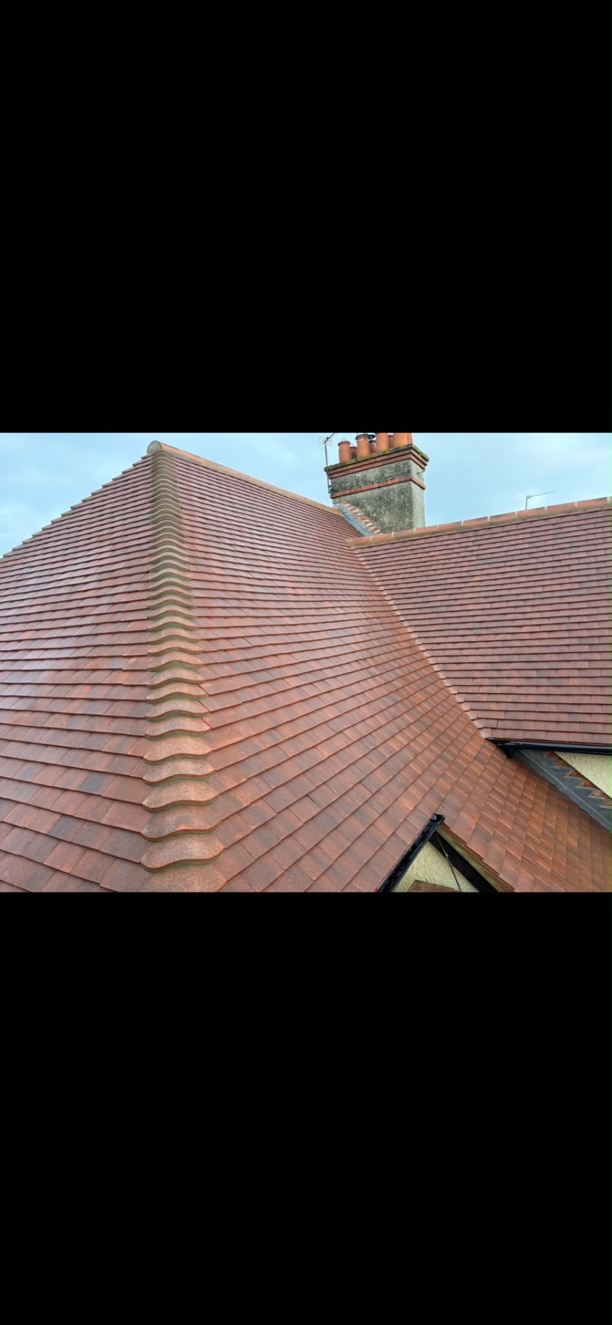 Clay tiled roof with bonnets, a tile valley and stepped lead flashing beside a brick chimney