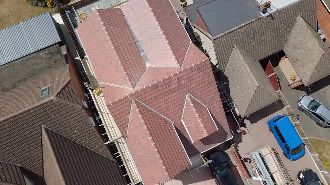 Concrete tiled roof on a multi-gabled house surrounded by scaffolding